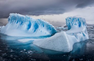 An aerial shot of icebergs in Antarctica under cloudy sky