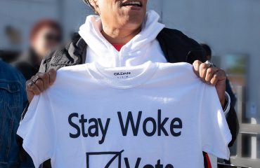 L'allora deputata statunitense Marcia Fudge mostra una maglietta che recita lo slogan "Stay Woke: Vote" (lett. "rimanete svegli: votate") (2018)
