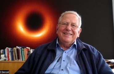 Il Premio Nobel Reinhard Genzel con alle spalle il Buco Nero da lui scoperto (elaboratzione AI)
